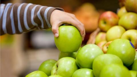 Child lifts an apple