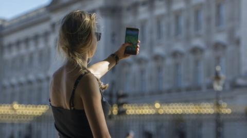 A woman playing Pokemon Go outside Buckingham Palace