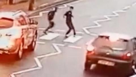 Driver overtakes vehicles while children are walking across a zebra crossing
