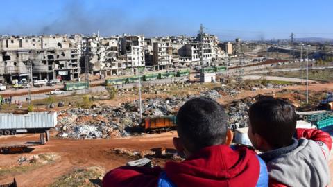 Children look out towards shattered buildings in Aleppo (15/12/16)