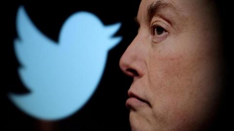 Elon Musk's side profile in front of a Twitter logo