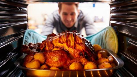 Man taking roast turkey out of oven