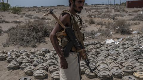 File photo showing a Yemeni pro-government fighter standing next to landmines that were laid by Houthi rebel fighters in al-Himah (22 September 2018)