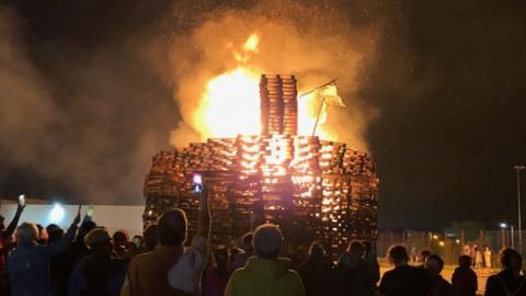 A crowd of people watch as the bonfire at Avoniel Leisure Centre burns