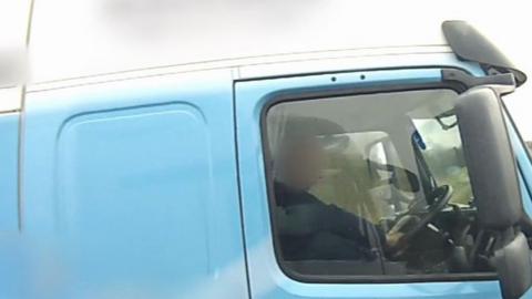 A HGV driver with his foot on the dashboard while travelling on the motorway