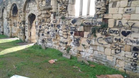 Graffiti across a long length of the walls of St Oswald's Priory