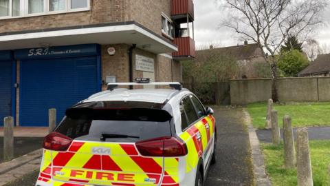 A fire car in front of a seven storey block of flats