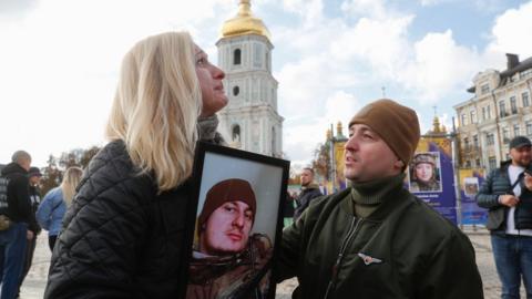 Natalia reacts as she holds a portrait of her lost son at the street exhibition 'Azov Regiment - Angels of Mariupol', which is dedicated to defenders from the 'Azov' unit of the National Guard of Ukraine, who gave their lives defending Mariupol from the Russian invaders in Kyiv, Ukraine, 14 October 2022