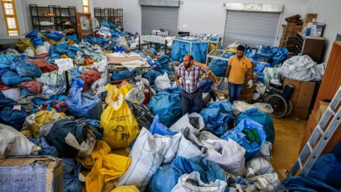 Palestinian postal workers sift through sacks of previously undelivered mail in the West Bank city of Jericho, 14 August 2018