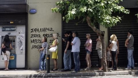 People queue at a cash machine in Athens, 27 June