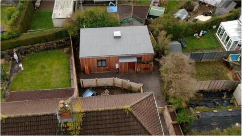 John's new home, pictured from above. Photo shows grey roof and wooden exterior, surrounded by neighbours' gardens