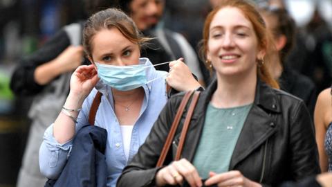 A shopper puts on a protective face covering in London