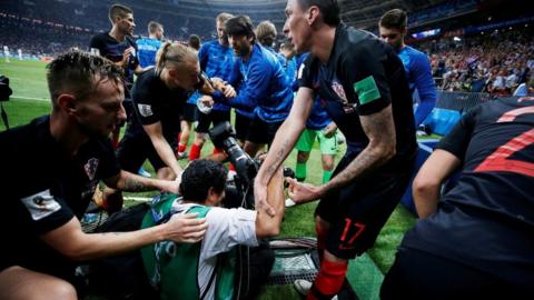 Croatia's Mario Mandzukic helps an AFP photographer Yuri Cortez to his feet after celebrating scoring their second goal