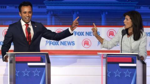 Republican presidential candidates, Vivek Ramaswamy and former UN Ambassador Nikki Haley both raising one finger as they speak at lecterns on the debate stage