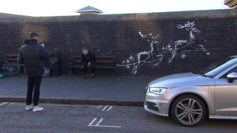 Resident in front of Banksy artwork