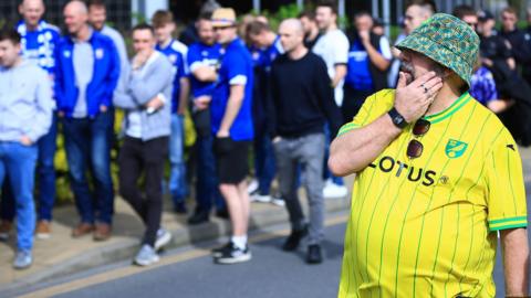 Norwich fan walks past Ipswich fans