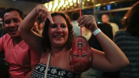 A woman laughs as he holds a mask depicting Republican presidential candidate Donald Trump during the election night party at a bar in Buenos Aires, Argentina, Tuesday, Nov. 8, 2016
