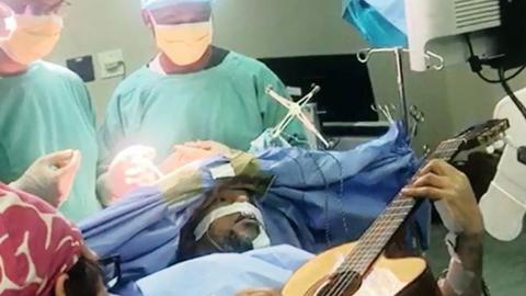 Musa Manzini plays his guitar on the operating table