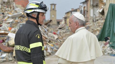 Pope Francis talks with a firefighter in front of rubble in Amatrice, Italy, 4 October 2016