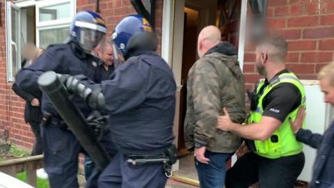 Police enter a house during a raid