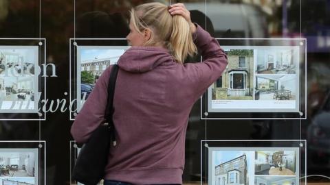 Woman looks in estate agent wndow