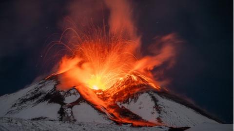 Plumes of smoke and sizzling lava rise from snow covered Mount Etna, Europe's most active volcano, as seen from Monte San Leo, Italy, November 24, 2023.