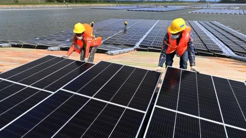 workers assemble solar panels in Singapore