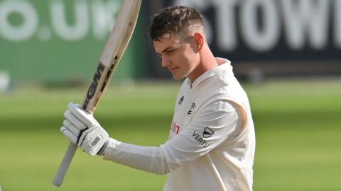 Freddie McCann holds his bat aloft after scoring a County Championship hundred for Nottinghamshire