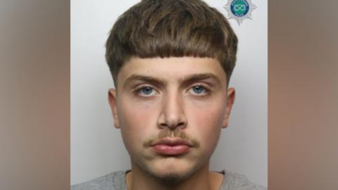 A man with short brown hair and a faint moustache