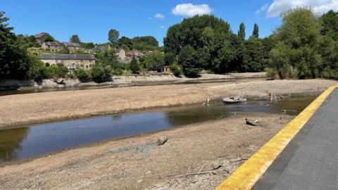 A low water level exposing bare mud and a sunken boat