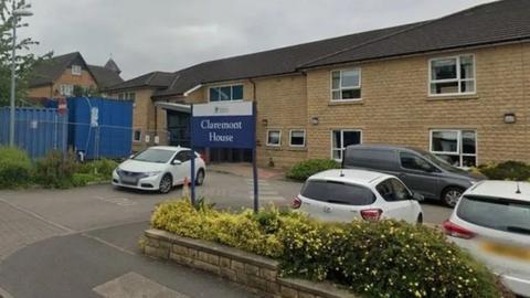 The outside of Claremont House in Huddersfield. Pictured is a modern beige-brick building with cars outside