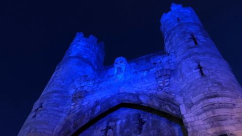 York Castle lit up in blue neon lighting by night.