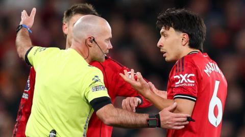 Referee Paul Tierney speaks with Lisandro Martinez of Manchester United after showing him a red card for pulling the hair of Dominic Calvert-Lewin of Leeds United