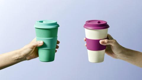 Two reusable insulted cups with two hands holding them.