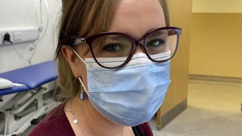 Female GP looks at camera while wearing a mask