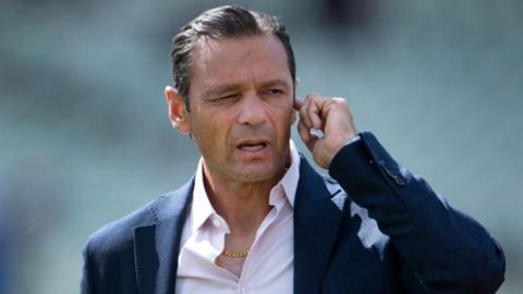 Mark Ramprakash puts his finger in his ear to listen to instructions via his ear piece
