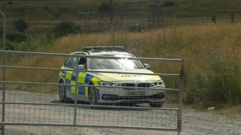 Police car at the entrance to the rave site