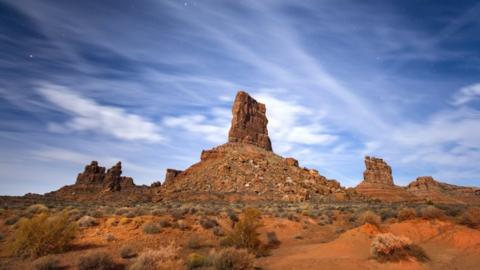 Sandstone buttes rise from the Valley of the Gods under a full moon in Bears Ears National Monument near Mexican Hat, Utah, USA