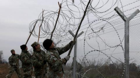 Macedonian Army engineers set a razor wire atop a fence on the border line between Macedonia and Greece