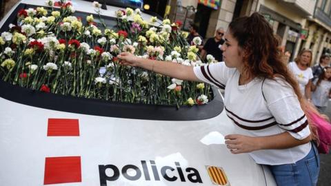 A woman displays a flower on the windshield of a vehicle of Catalan police, known as Mossos d'Esquadra during a pro-referendum concentration in Barcelona on September 24, 2017.