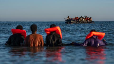 Migrants wait in the sea to try and board a dinghy to cross the English Channel on August 25, 2025 in Gravelines, France. 