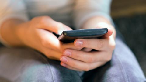 Stock image of a teenager holding a phone