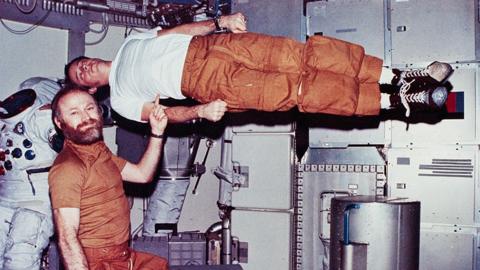 Jerry Carr demonstrates weightlessness by pretending to hold up Ed Gibson with one finger