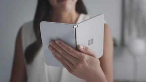 A woman looking at a new dual-screen device Surface Duo