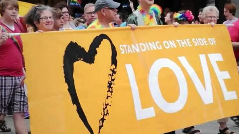 People holding a banner saying "Standing on the side of love"