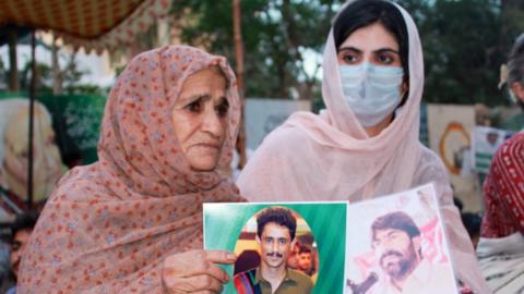 Sammi Deen Baloch (right) holds up a photograph of her father, who had been missing since 2009