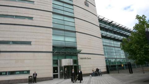 Large grey building with green tinted glass along the centre. Laganside Courts is written on the right hand side of the door.