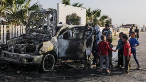 Palestinians inspect a World Central Kitchen vehicle that was destroyed in an Israeli air strike south of Deir al-Balah, in the Gaza Strip (2 April 2024)