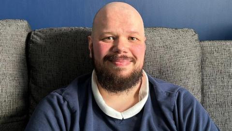 A man with a beard smiles at the camera