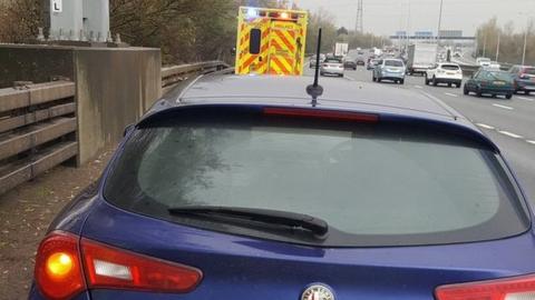 A car and an ambulance parked on the hard shoulder of the M25